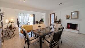 Un saló modern amb zona de menjador, una llar de foc i una vista per una finestra gran.