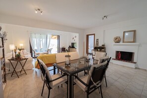 Ein modernes Wohnzimmer mit Essbereich, Kamin und Blick durch ein großes Fenster.