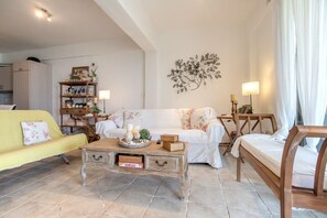 Ein Wohnzimmer mit einer Couch, einem Couchtisch, einem Bücherregal und einem Wandbild.