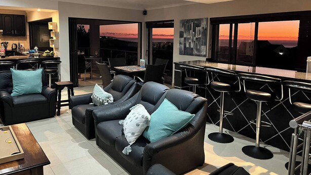 Un salon moderne comprenant un canapé, des fauteuils, une table à manger et un coin bar.