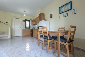 Eine Küche mit Holzschränken, einem weißen Kühlschrank und einem Esstisch mit vier Stühlen.