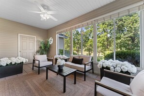 A sunroom with a ceiling fan, large windows, a sofa, a coffee table, and potted plants. - Birdies View Golf View Patio (Branson)