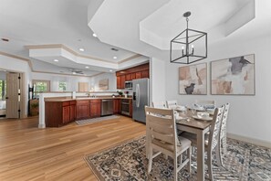A spacious kitchen with wooden cabinets, a central island, and a dining area with a table set for four. - Birdies View Golf View Patio (Branson)