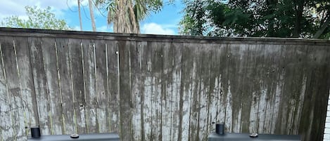 Dos parrillas para exterior negras con ruedas, con las marcas 'NEXGRILL' y 'OAKFORD', sobre un patio de concreto con una cerca de madera al fondo.