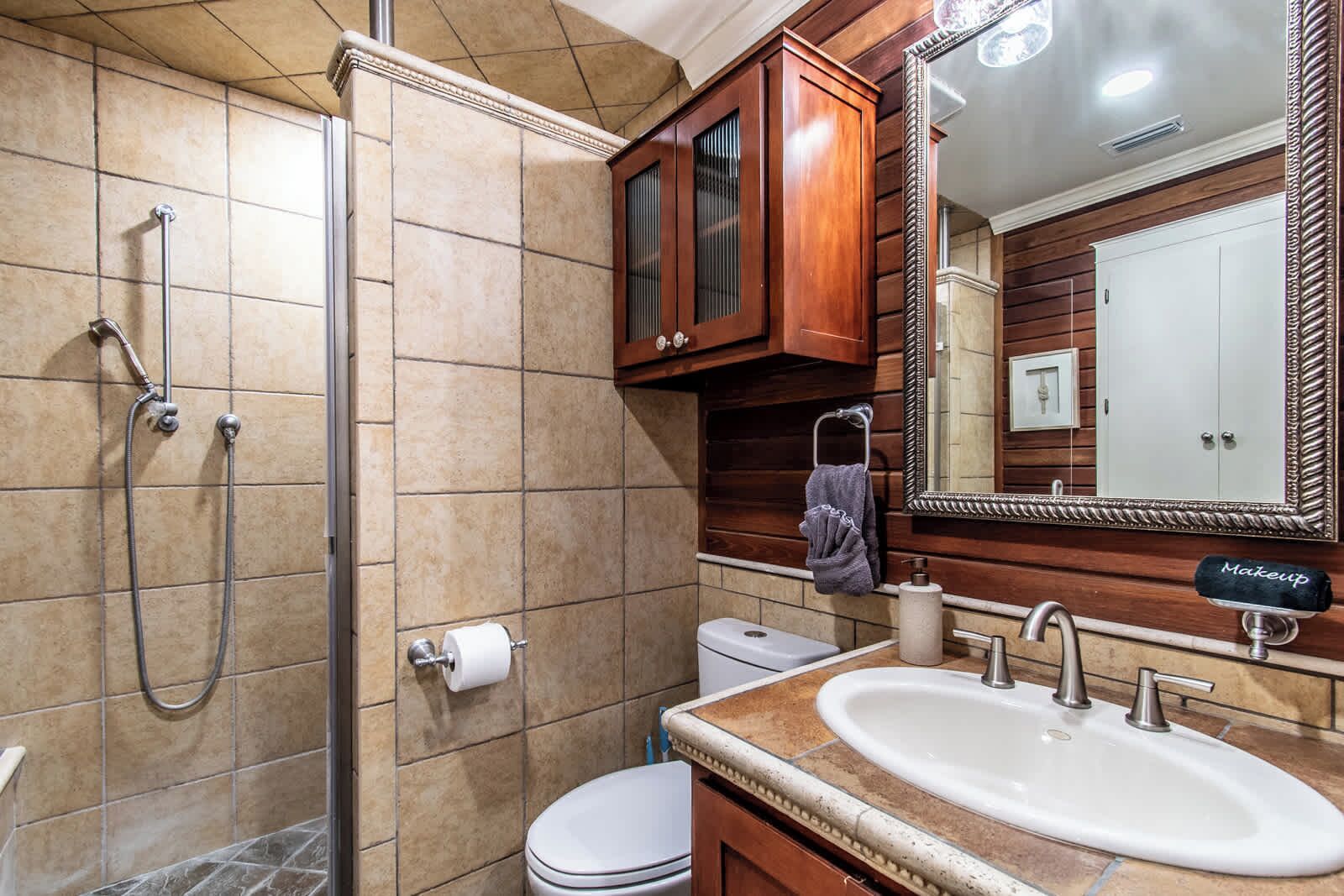 A bathroom with a shower, toilet, sink, and vanity.