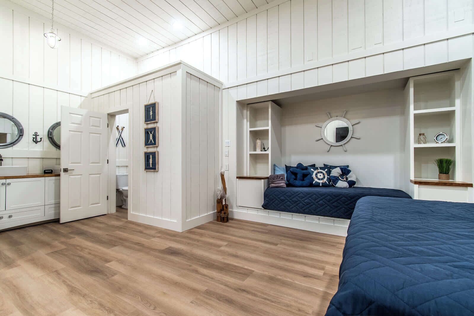 A nautical-themed bedroom with a bed, built-in shelves, and a circular mirror.