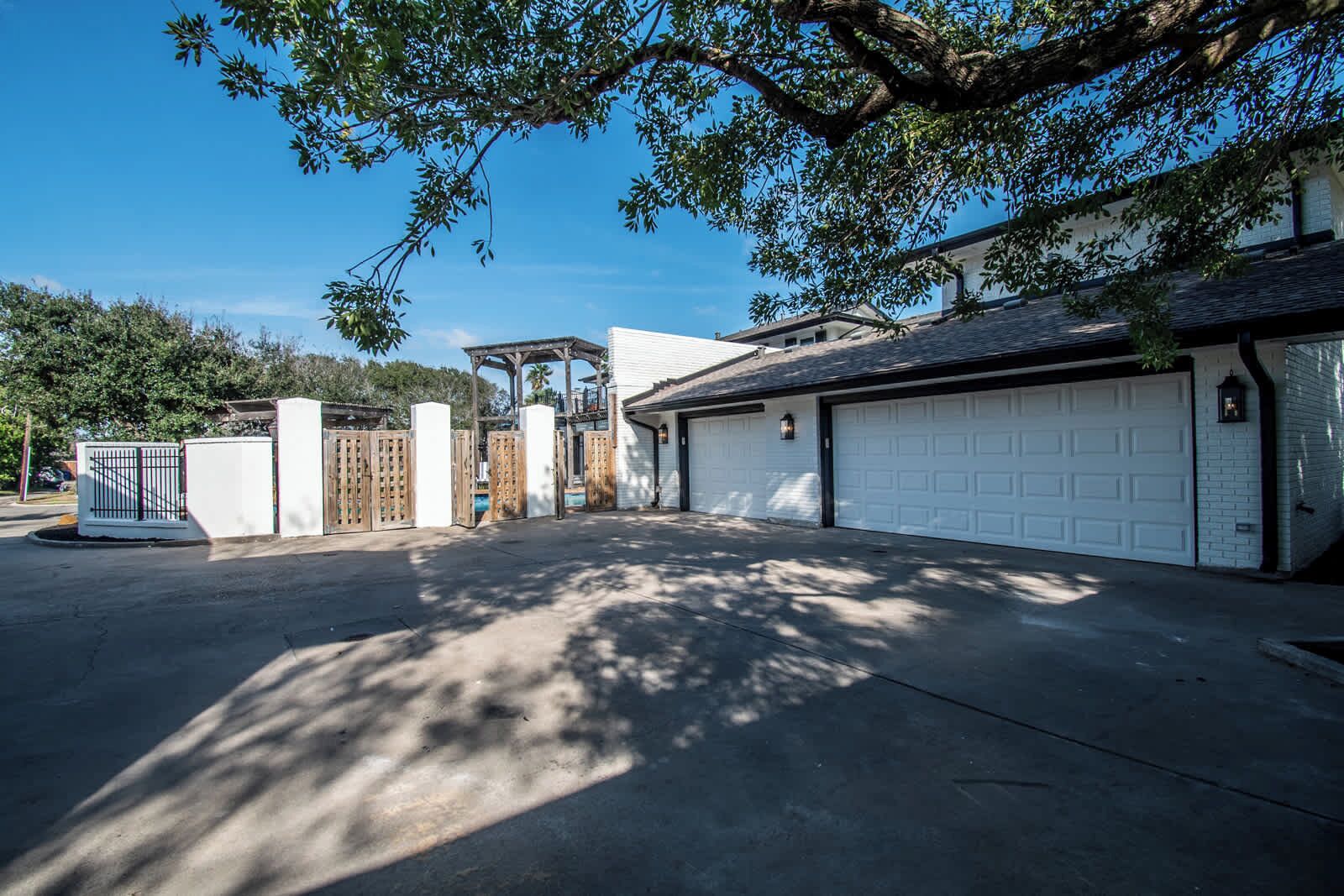 Ein befestigter Zugangsweg führt zu einer Garage mit überdachtem Carport und weißer Garagentür.