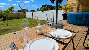 A wooden deck with a table set for two, featuring white plates, cutlery, and glasses. - Cozy lodge with a private hot tub and air conditioning (La Trinité-Surzur)