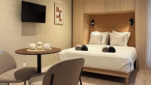 A modern hotel room with a bed, a TV, a small table with cups, and chairs. - Cozy lodge with a private hot tub and air conditioning (La Trinité-Surzur)