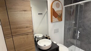 A modern bathroom with a wooden vanity, a round sink, a toilet, a glass shower enclosure, and a wall-mounted mirror. - Cozy lodge with a private hot tub and air conditioning (La Trinité-Surzur)