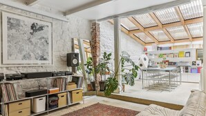 A spacious living area with a large window, a bookshelf, a coffee table, and a sofa. - Apartment 'Loft Design Center Paris 11th' with Wi-Fi (Paris)
