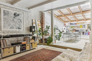 A spacious living area with a large window, a bookshelf, a coffee table, and a sofa. - Apartment 'Loft Design Center Paris 11th' with Wi-Fi (Paris)