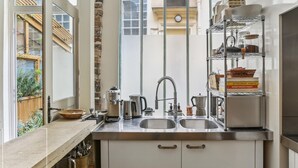A compact kitchen with a double sink, stainless steel appliances, and a metal shelf with kitchenware. - Apartment 'Loft Design Center Paris 11th' with Wi-Fi (Paris)