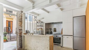 A modern kitchen with a central island, stainless steel appliances, and a brick accent wall. - Apartment 'Loft Design Center Paris 11th' with Wi-Fi (Paris)