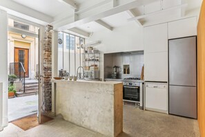 A modern kitchen with a central island, stainless steel appliances, and a brick accent wall. - Apartment 'Loft Design Center Paris 11th' with Wi-Fi (Paris)