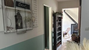 A hallway with a shelf displaying decorative items, a staircase, and a potted plant. - Quiet room in a house between Mont Ventoux and dentelles de Montmirail (Saint-Hippolyte-le-Graveyron)