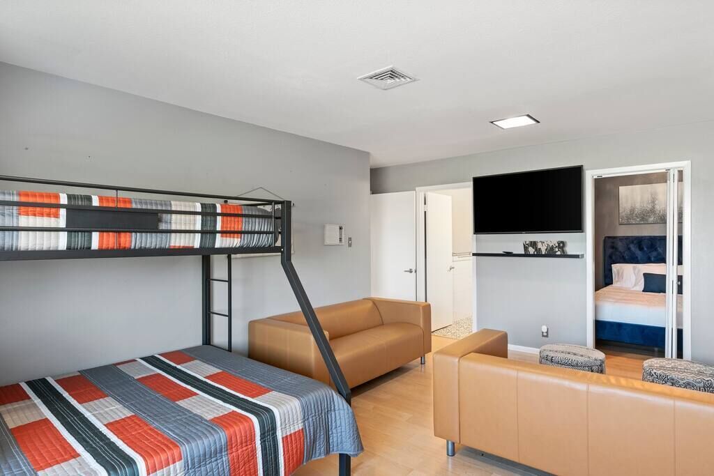 Een kleine kamer met een stapelbed, een slaapbank en een televisie.