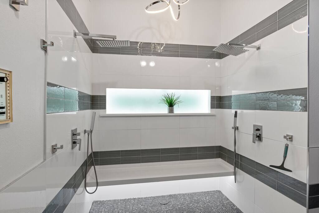 A modern bathroom with a glass-enclosed shower, a window with a plant, and a tiled floor.