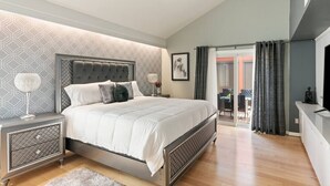 Une chambre à coucher moderne avec un grand lit, une table de chevet et une lampe de chevet, ainsi qu’un luminaire au plafond.