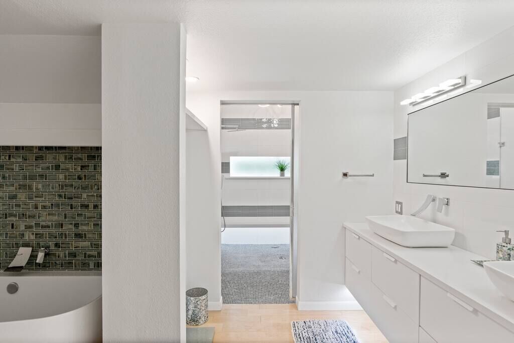 A modern bathroom with a bathtub, a large mirror, and a white vanity.