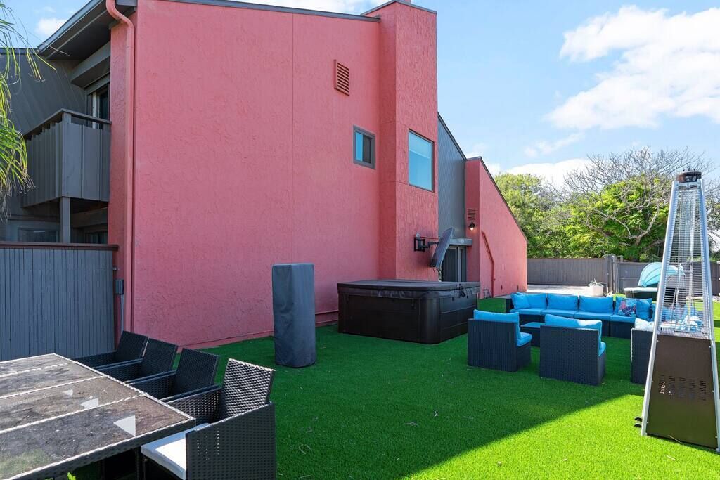 A patio area with a red building, outdoor furniture, and artificial grass.