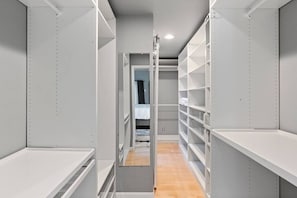 A narrow walk-through closet with open shelving and a bed in the background. - Ocean Drive Oasis w Hot Tub Awaits (Corpus Christi)