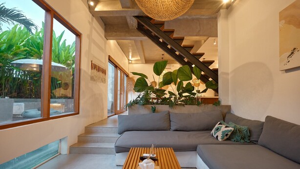 Ein modernes Wohnzimmer mit einer Couch, einem Holztisch und einer Treppe.