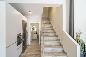 A modern kitchen with stainless steel appliances, a wooden staircase, and a hanging mirror. - Cubo's La Brisa del Valle Rural House / Private pool / Air conditioning / BBQ / Free Wi-Fi (Alhaurín el Grande)