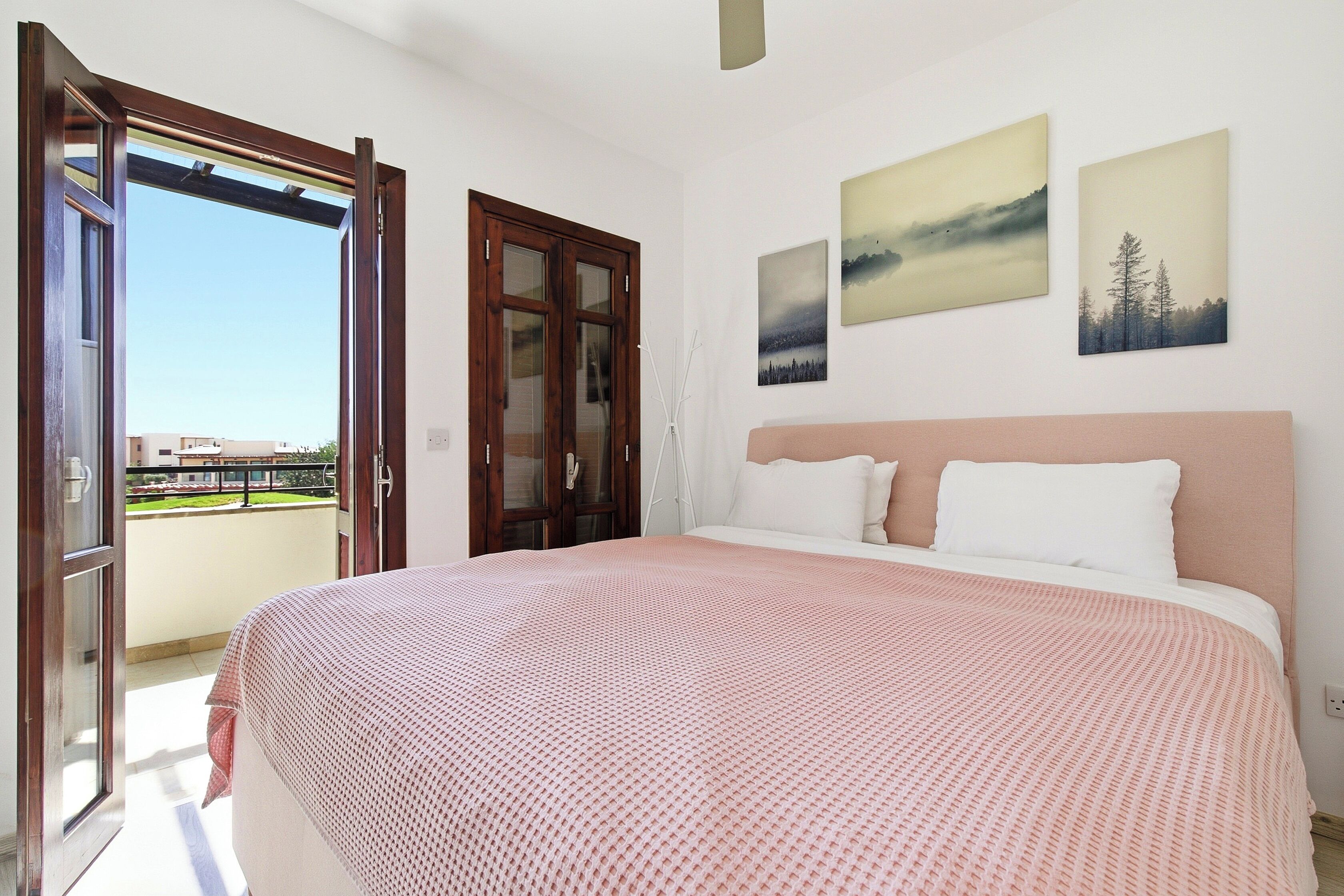 A bedroom with a bed, a window, and two wall-mounted pictures.