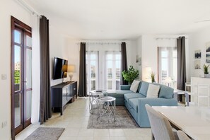 A modern living room with a sofa, TV, and dining area. - Beautiful Apartment Callysta PA11 (Kouklia)