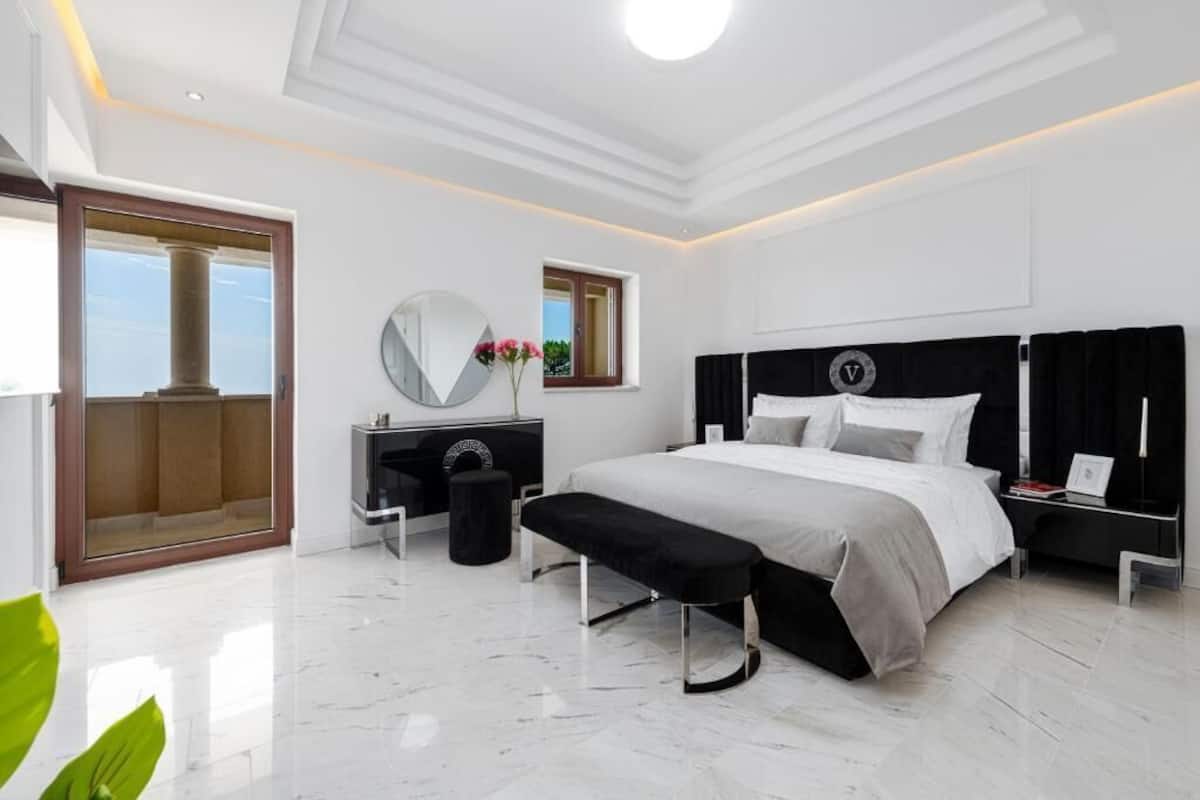 Un dormitorio moderno con una cama grande, una mesita de noche, un espejo y una ventana.