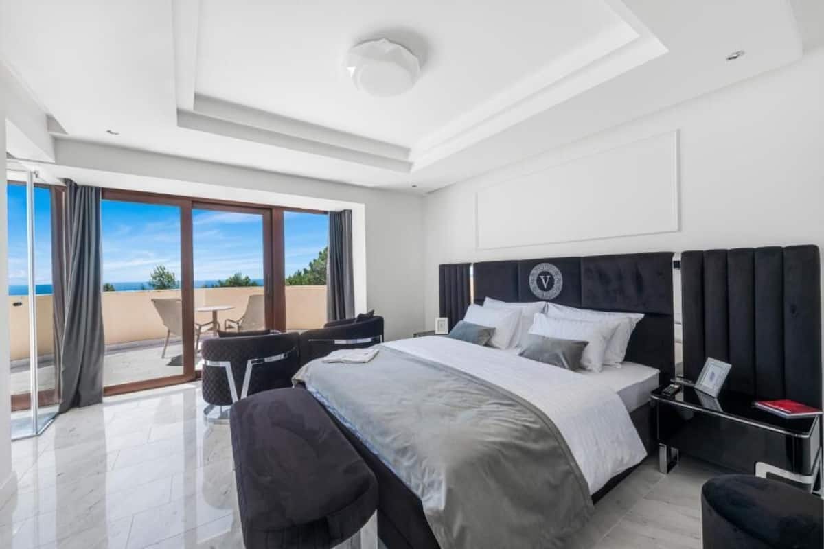 Una habitación de hotel moderna con una cama grande, un escritorio y un balcón con vistas.