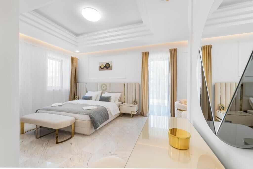Un dormitorio moderno con cama, mesitas de noche, un banco y un espejo.
