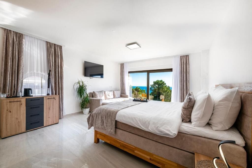 Ein Schlafzimmer mit Bett, Fernseher, Fenster mit Blick und einem Holzschrank.