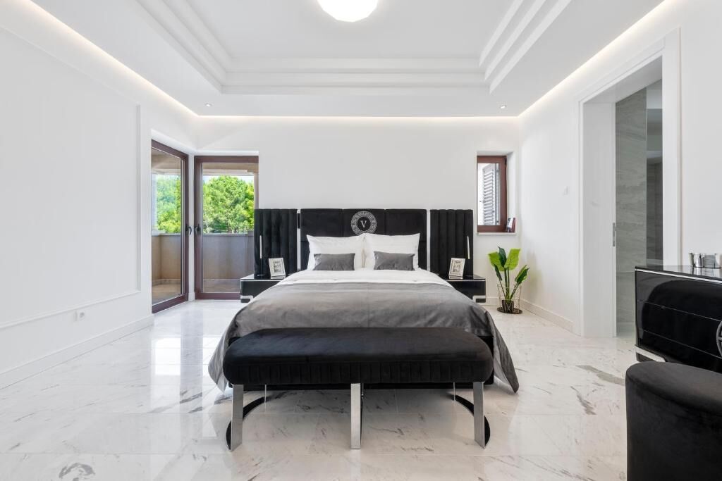 Un dormitorio moderno con una cama grande, una mesita de noche y una planta en maceta, con vistas al exterior.