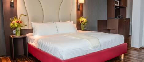 Una habitación de hotel moderna con una cama grande, suelo de madera, un armario empotrado y lámparas de noche.