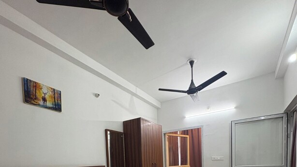 Un dormitorio con una cama, dos ventiladores de techo, un armario, un espejo y una puerta que da a otra habitación.