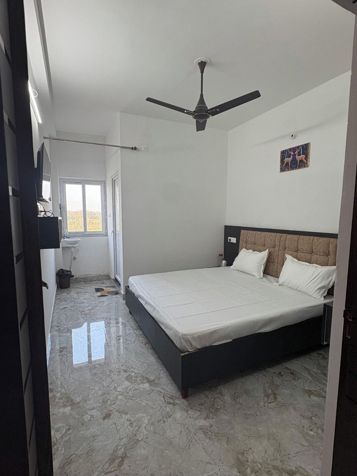 A bedroom with a bed, a ceiling fan, a window, and a wall-mounted picture.