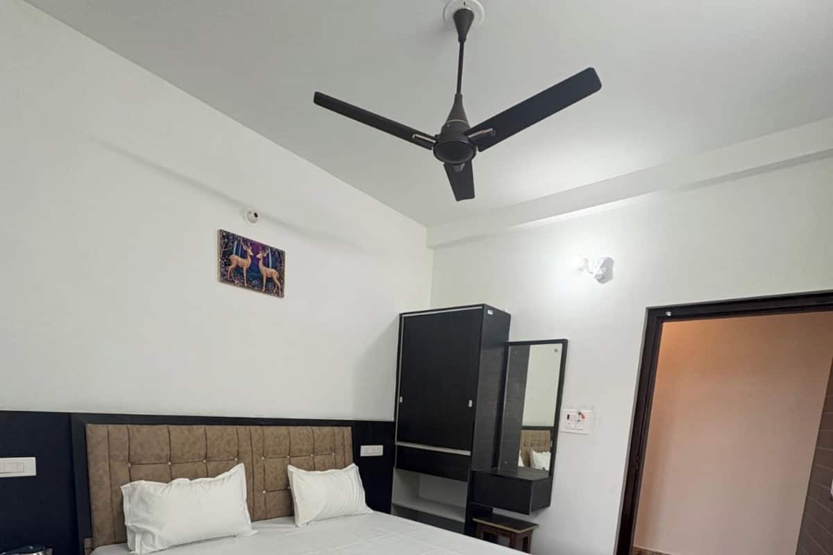 Habitación de hotel con una cama grande, un ventilador de techo, un armario, un televisor y una puerta que da a otra habitación.