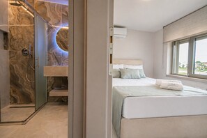 A bedroom with a bed, a window, and a shower area with a marble wall. - Aria Prive Pool Villa Νο2 by RentalsPro - Portaria Beach (Nea Moudania)
