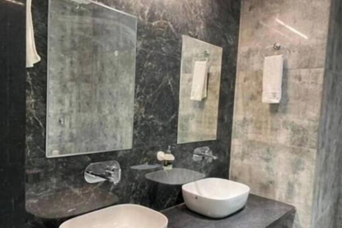 Un baño con dos lavamanos, un espejo y un perchero para toallas.