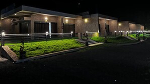 A modern building with multiple entry points, a well-lit entrance, and a landscaped area with steps leading to the main doors.