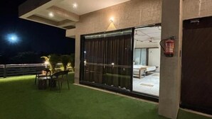 A modern building with a large glass door, a fire extinguisher, and a small outdoor seating area with chairs and a table.