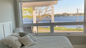 A bedroom with a large window, a bed, a ceiling fan, and a view of a lake. - Luxury Spring Lake Retreat, 8BR w/ Lake Views & Ensuite Baths (Spring Lake)