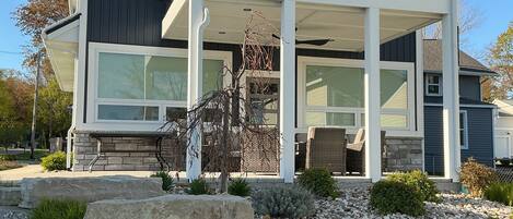 A modern two-story house with a balcony, stone landscaping, and a clear sky.