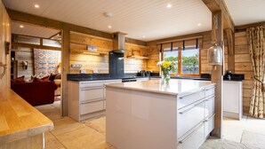 A modern kitchen with wooden walls, a central island, and a view of the outdoors.