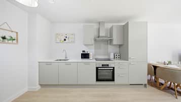 Eine moderne Küche mit weißen Schränken, einem eingebauten Backofen, einer Mikrowelle und einem Essbereich mit Tisch und Stühlen.