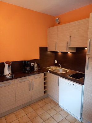 A compact kitchen with a sink, coffee maker, and dishwasher. - Bright cabin apartment for 4 people with a pool view (Agde)