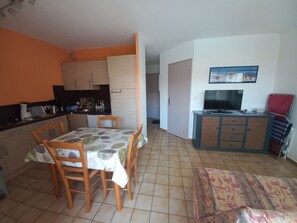 A compact living space with a dining area, kitchenette, and a television. - Bright cabin apartment for 4 people with a pool view (Agde)