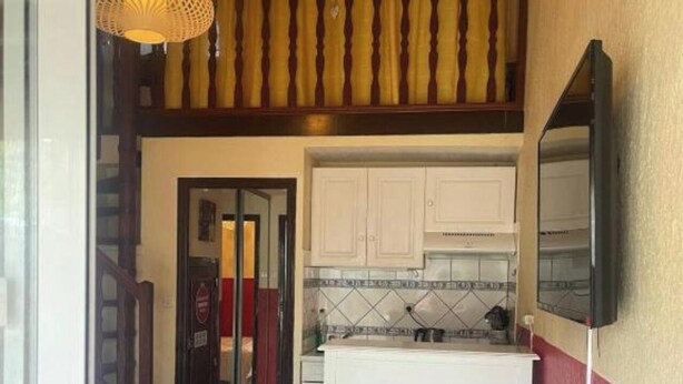 A kitchen with white cabinets, a tiled backsplash, and a small island. - 88 Heliovillage (Agde)